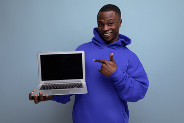 handsome african young consultant in stylish hoodie with laptop to show ads on background with copy space