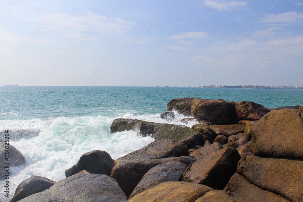 Wall mural stone seashore in sri lanka. unawatuna beach, dark brown rocks, background, copy space for text