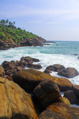 Fototapeta na wymiar The mound of stones on the seashore. Sri Lanka, blue sky, copy space for text