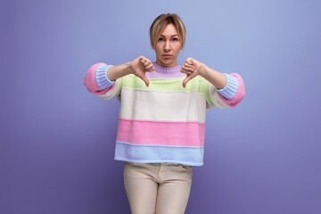 portrait of distressed cute blonde young woman showing dislike on purple background