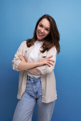 well-groomed smiling brunette 30 year old female person is dressed in a shirt and jeans on a blue background