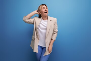blond business woman in a beige jacket eavesdrops on a conversation on a studio background