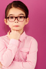 Girl child in portrait, glasses and thinking with questioning expression, smart and vision isolated on pink background. Intelligent, geek or nerd with female kid in studio, thoughtful in eyewear