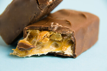 Delicious chocolate bars with nougat and peanuts on a blue background