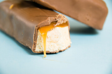 Tasty chocolate bar with white nougat and caramel on a blue background