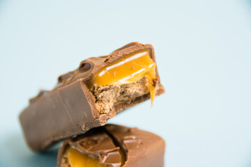 Appetizing pieces of a chocolate bar with caramel macro on a blue background