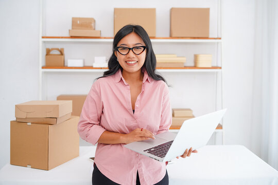 Photo of smiling Asian business woman, successful entrepreneur, elegant professional company executive ceo manager standing in office holding laptop - Powered by Adobe