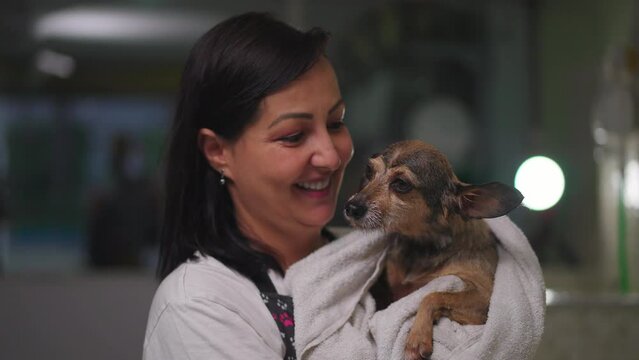 Portrait Of A Woman Holding Dog Wrapped In Towel Standing Inside Pet Shop. Joyful Female Small Business Owner Of Local Store. Job Occupation Service Concept