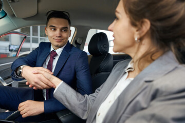 Happy businessman and women shaking hands sitting in car