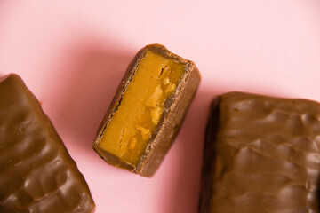 Flatlay, sweet chocolate bar with salted caramel macro on pink paper background with copy space