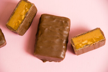 Flatlay, sweet chocolate bar with salted caramel macro on pink paper background with copy space