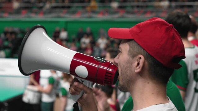 Angry man scream megaphone sport stadium. Crazy mad fan shout bullhorn close up. Anger agressive male cheer team. Furious person yell loudspeaker. Evil guy loss win goal. Crowd watch game cup match.