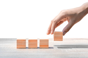 Hand putting wooden cube block on wooden table, on white background Business ideas for a successful...