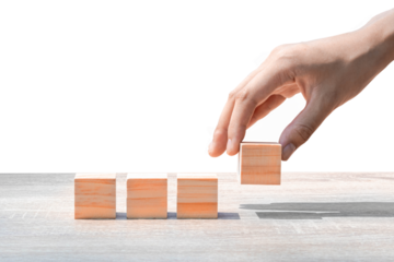 Hand putting wooden cube block on wooden table, on white background Business ideas for a successful growth process.PNG