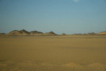 Fototapeta na wymiar Deserto di pietre e sabbia, con montagne sullo sfondo, sul percorso per Abu Simbel