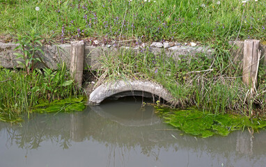 Water flows through concrete culvert in ditch