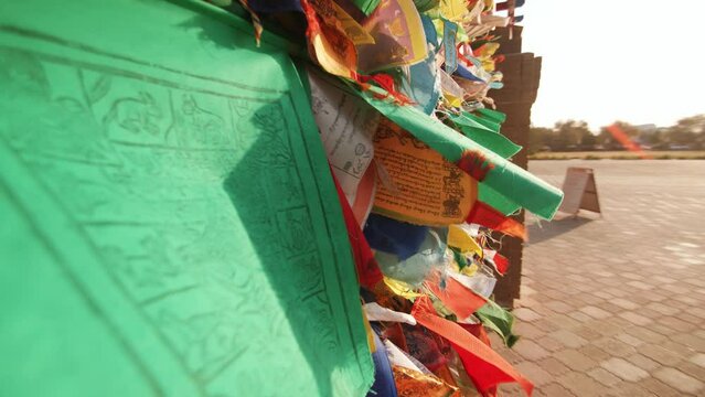 Multi-colored ribbons and small flags with prayers are tied to the gates of buddhist temple