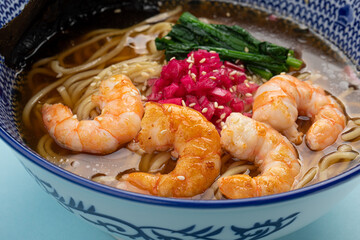 Portion of ramen noodle soup with shrimp on blue background