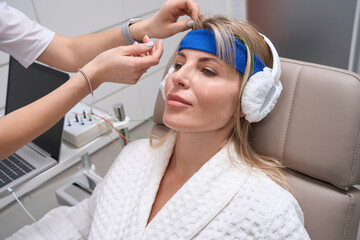 Naklejka premium Beautiful woman on bioacoustic correction procedure in a medical center
