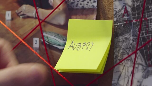 Note with handwritten inscription autopsy stuck on the evidence board