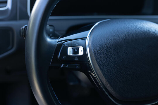Cruise control, speed limit and volume buttons on modern car steering wheel, interior details. Car with adaptive cruise control radar