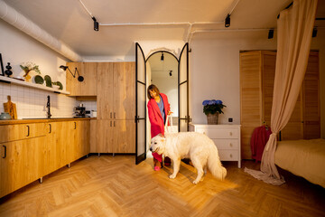 Dog meets its owner at the doorway of living room at home. Concept of a happy homecoming when your...