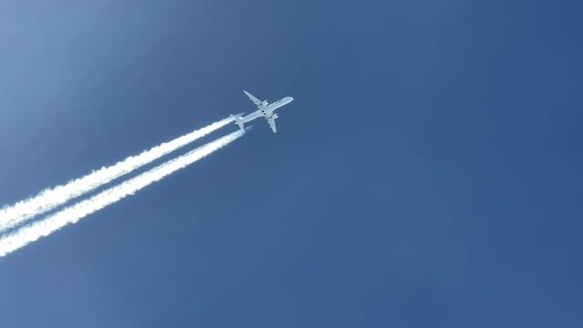 A jet airplane, white color, shot from an airplane’s cabin flying 2 levels bellow. Pilot’s perspective, flying 2 levels bellow at Mach number .78, same track. Wake visible. Daylight.