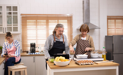 Multi-generational family members explore new and tasteful recipes on a tablet, make healthy food choices, cook, and enjoy meals together. Family gatherings help renew and strengthen relationships.