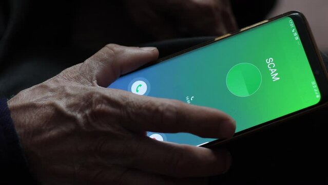 concept of telephone fraud against the elderly. a pensioner holds a smartphone on the screen of which the inscription is fraud. telephone scammers call old people