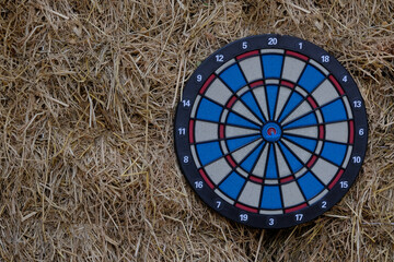 Black, red, blue and white round dart boards hang on a vintage straw wall outside. Entertaining in the garden or terrace - 601643216
