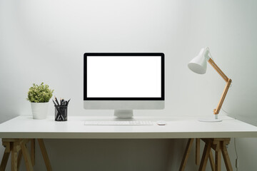 Modern workplace with bank screen of desktop computer on desk. White empty screen for graphic display montage