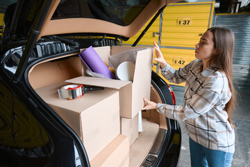Attentive woman packs goods in the trunk