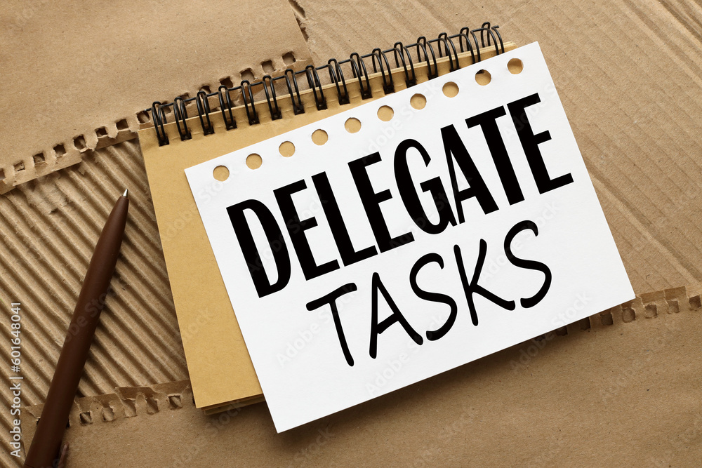 Poster delegate tasks written on notebook page with brown pen on the right