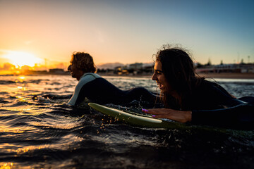 Two surfers with surfboard prepares to hit the waves at sunset. © Zoran Zeremski