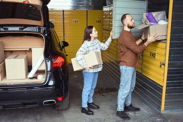 Young man and woman stacking merchandise for storage