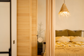Interior view of bedroom in beige tones with straw lampshade and wardrobe shutters. Boho style natural materials © rh2010