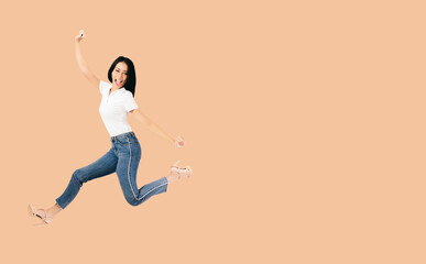 Fototapeta na wymiar Cheerful positive asian lady jumping on air raised fists hand look at camera Happy girl jumping having fun rising hands up Happy Asia woman smiling and flying celebrating success on air full body jump