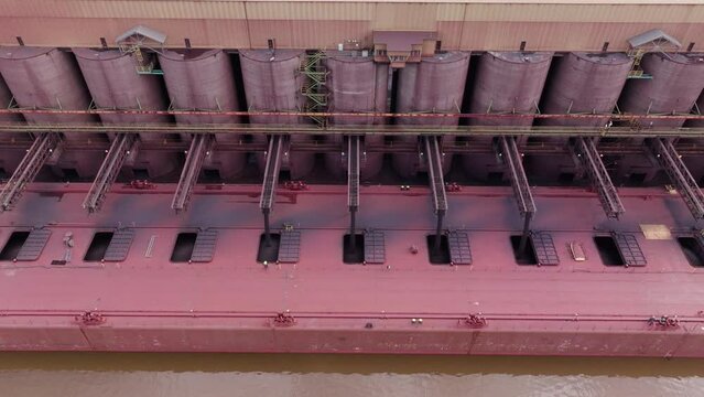 Conveyor belts loading iron taconite into haul of large freight ship at ore dock in Wisconsin