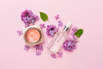 Composition with cosmetic bottles and flowers on color background, top view