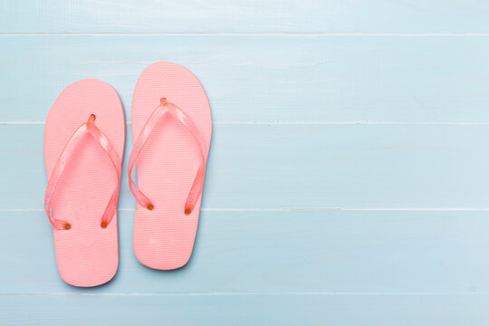 Bright flip flops on wooden background, top view