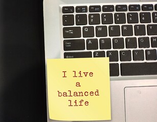 Note stick on laptop keyboard with text written I LIVE A BALANCED LIFE, positive mantra affirmation...