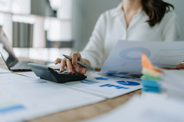 Young asian female work with financial papers at home count on calculator before paying taxes receipts online, planning budget glad to find chance for economy saving money, audit concepts.