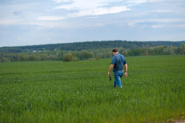 Naklejka na ściany i meble A young agronomist inspects the crops. Yield increase. The problem of world hunger. Organic cultivation of crops.Agriculture