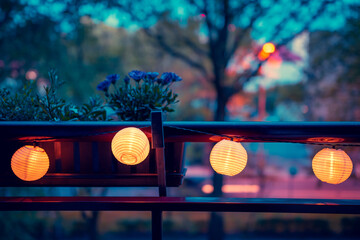 A lighted garland with solar lamps hung on the balustrade of the balcony. Mood light. African daisy in a balcony pot. Evening