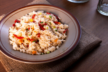 Fried race in a plate on a burlap mat. Fried rice is an Indo-Chinese dish with scallions, red chilies and carrots