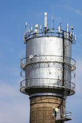Various antennas on an old water tower in the background of the sky