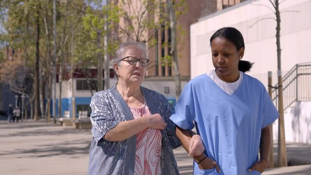 Footage of a young latin caregiver out for a walk outdoors with her female senior patient.