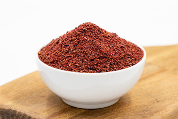 Sumac isolated on white background. Dried ground red Sumac powder spices in wooden bowl. Close up