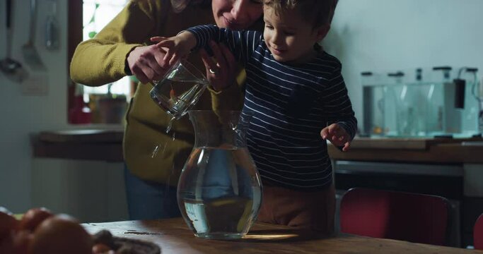 Portrait of Little Excited Boy Receiving his First Pet Goldfishes From his Mother in a Kitchen at Home. Woman Encouraging and Supporting her Toddler's Sense of Curiosity and Responsability