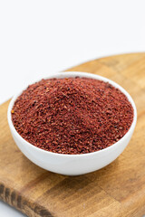 Sumac isolated on white background. Dried ground red Sumac powder spices in wooden bowl